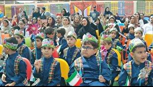 پرچم سه‌رنگ ایران در میان میدان مدرسه با لبخند کلاس اولی‌ها